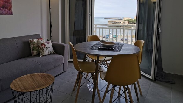 A balcony with a dining table and chairs, a sofa, and a lamp. - Andreas Cozy Lovely House (Heraklion)