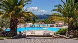 Ein Poolbereich mit Palmen, einem Pool und Blick auf das Meer.
