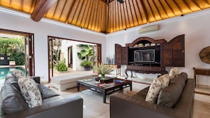 A spacious living room with a high ceiling, a television, and a comfortable seating area. - Villa Rubina (Seminyak)
