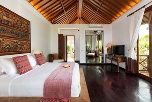 A spacious bedroom with a large bed, a wooden ceiling, a mirror, a TV, and a view of the outdoors.
