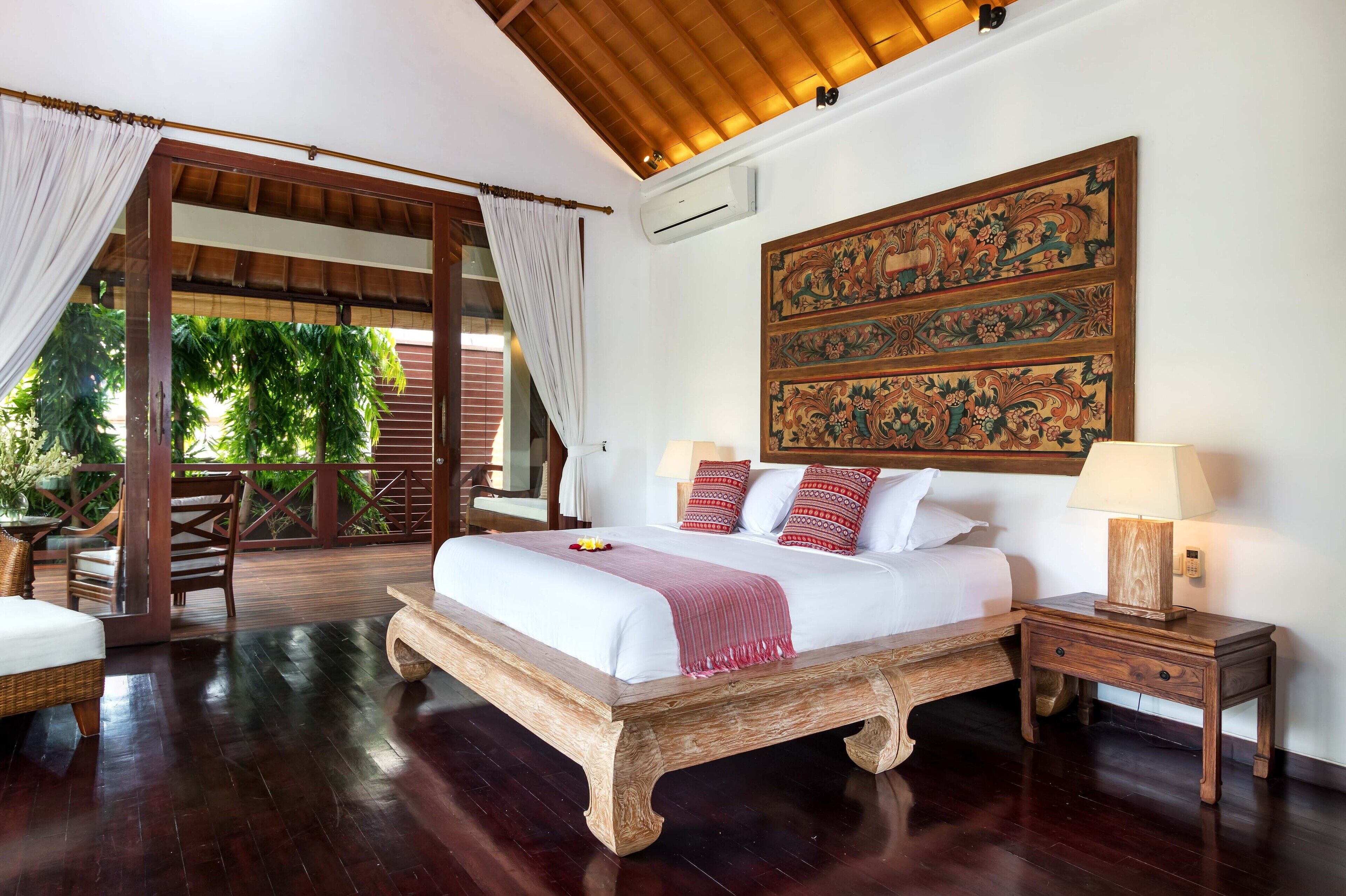 Un dormitorio espacioso con una cama grande, mesitas de noche de madera y un tapiz tradicional en la pared.