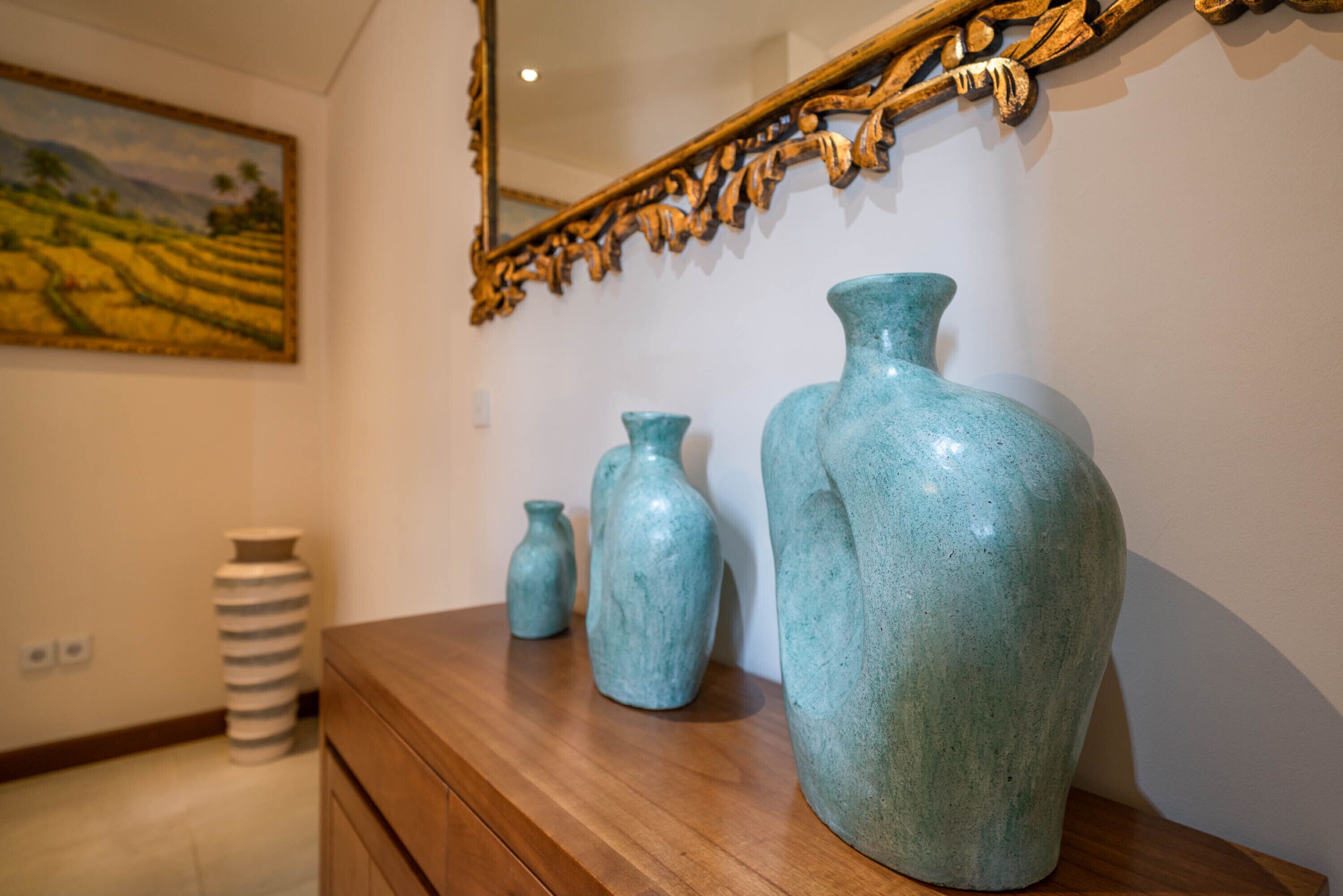 Une commode en bois surmontée de trois vases en céramique de différentes tailles.