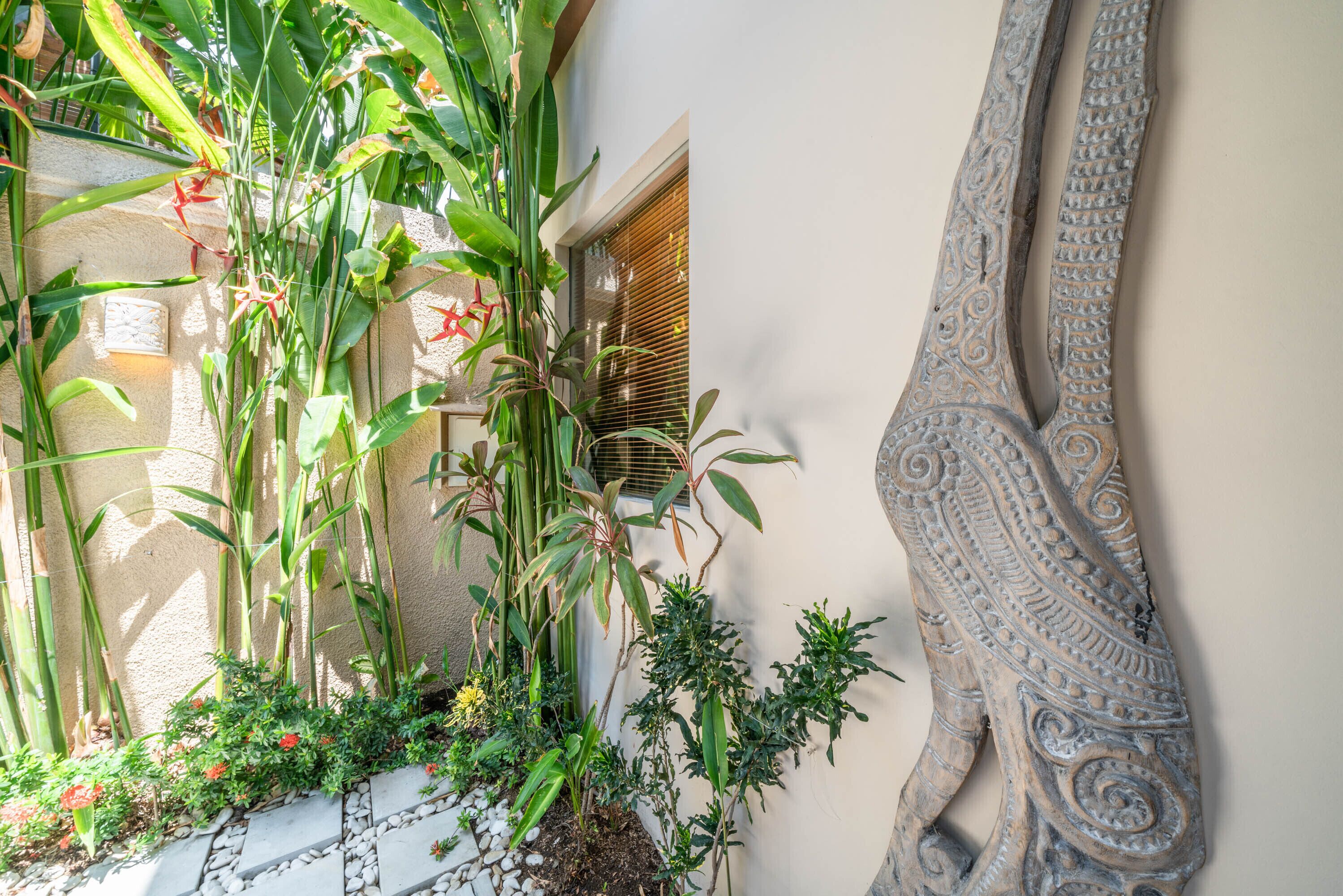 A garden with various plants and a decorative wall piece.