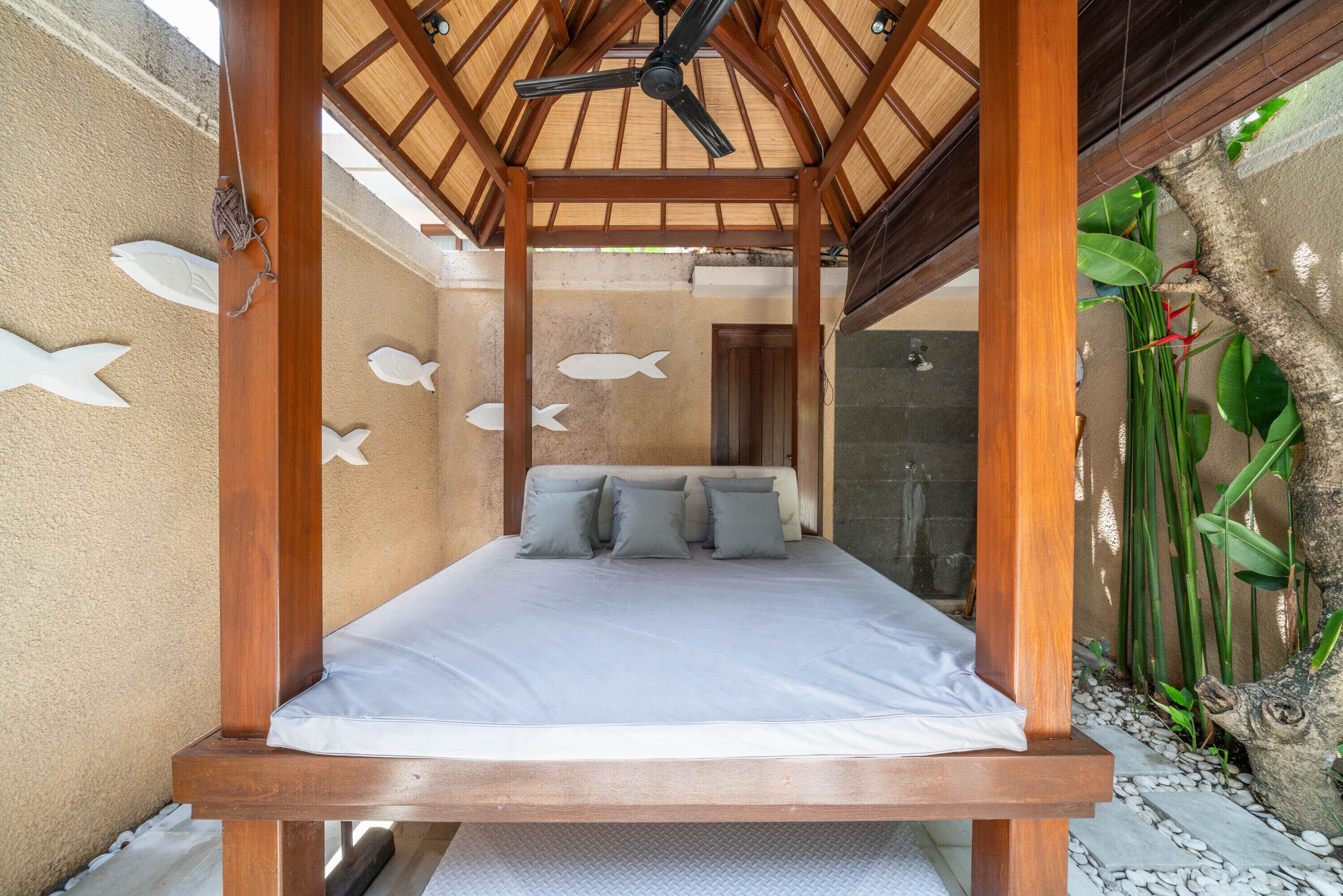 Ein Zimmer mit einem Bett, einem Deckenventilator und Wandbildern mit Fischmotiven.