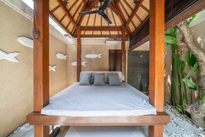 A room with a bed, ceiling fan, and fish wall art. - Villa Seacluded 1 (Seminyak)