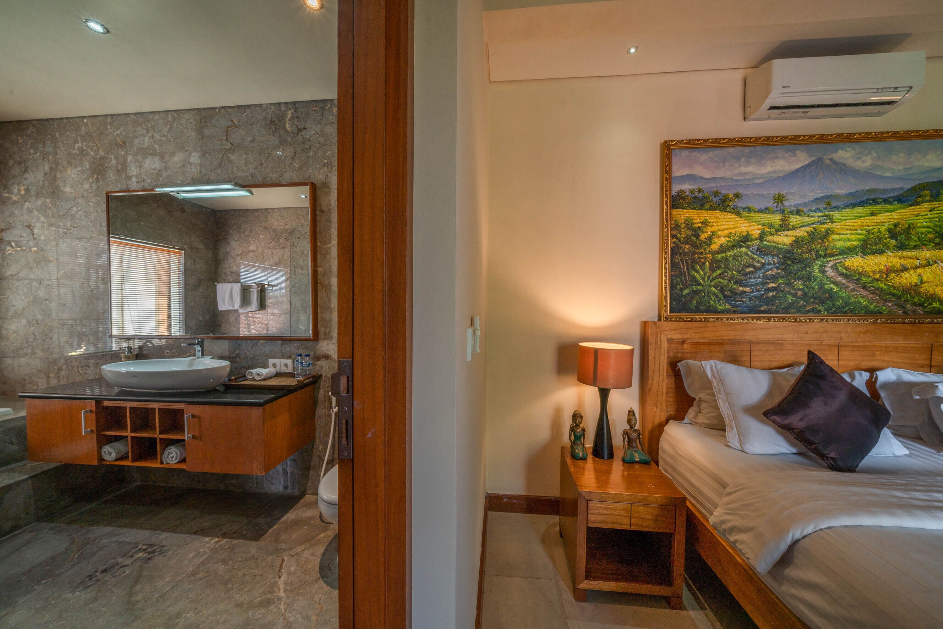 Une salle de bain avec un lavabo en marbre, un meuble-lavabo en bois et un grand miroir.