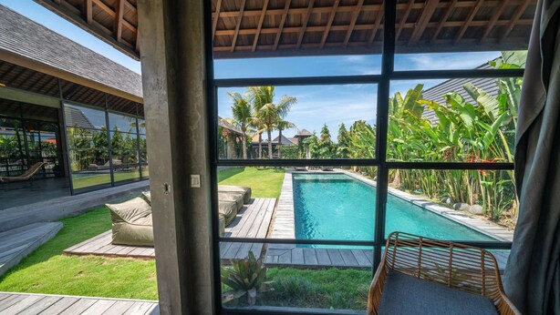 Ein moderner Poolbereich mit freiem Blick durch große Fenster, einer Holzterrasse und Sitzgelegenheiten im Freien.