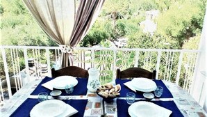 Une table de balcon dressée avec des assiettes, des verres et un centre de table décoratif.