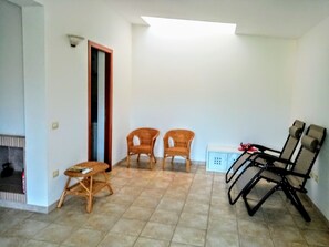 A room with two wicker chairs, a small table, a sofa, and a cabinet. - a Stone's Throw Away From Foximannana in the Foreground - Tertenia (Tertenia)