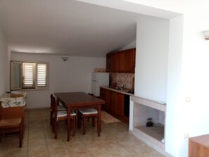 Una cocina compacta con armarios de madera, una mesa de comedor con sillas y una pequeña encimera.