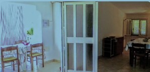 A room with a dining area, a kitchen, and a door leading to another space.