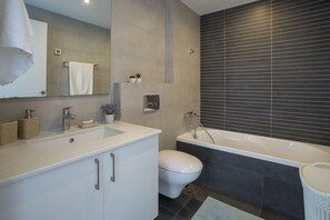 Un baño moderno con un tocador blanco, un inodoro y una bañera.