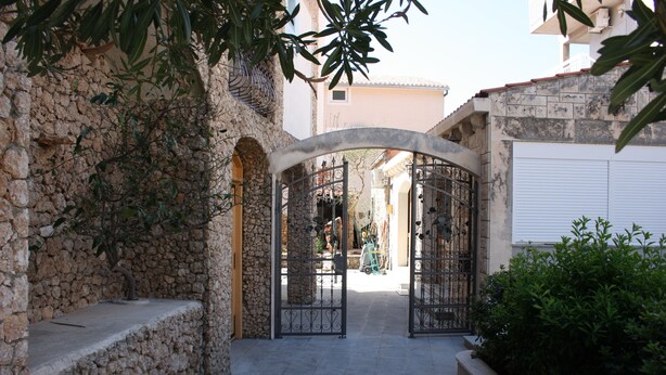 A stone pathway leading to a gated entrance with a view of a building in the background. - Relax Adriatic House (Omis)