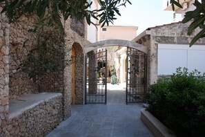 A stone pathway leading to a gated entrance with a view of a building in the background. - Relax Adriatic House (Omis)