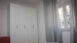 A bedroom with a bed, a wardrobe, and a window with curtains. - Relax Adriatic House (Omis)