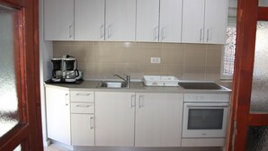 A kitchen with white cabinets, a sink, a coffee maker, and an oven. - Relax Adriatic House (Omis)