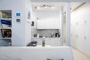 A compact, modern room with a kitchenette, a bed, and a wardrobe.