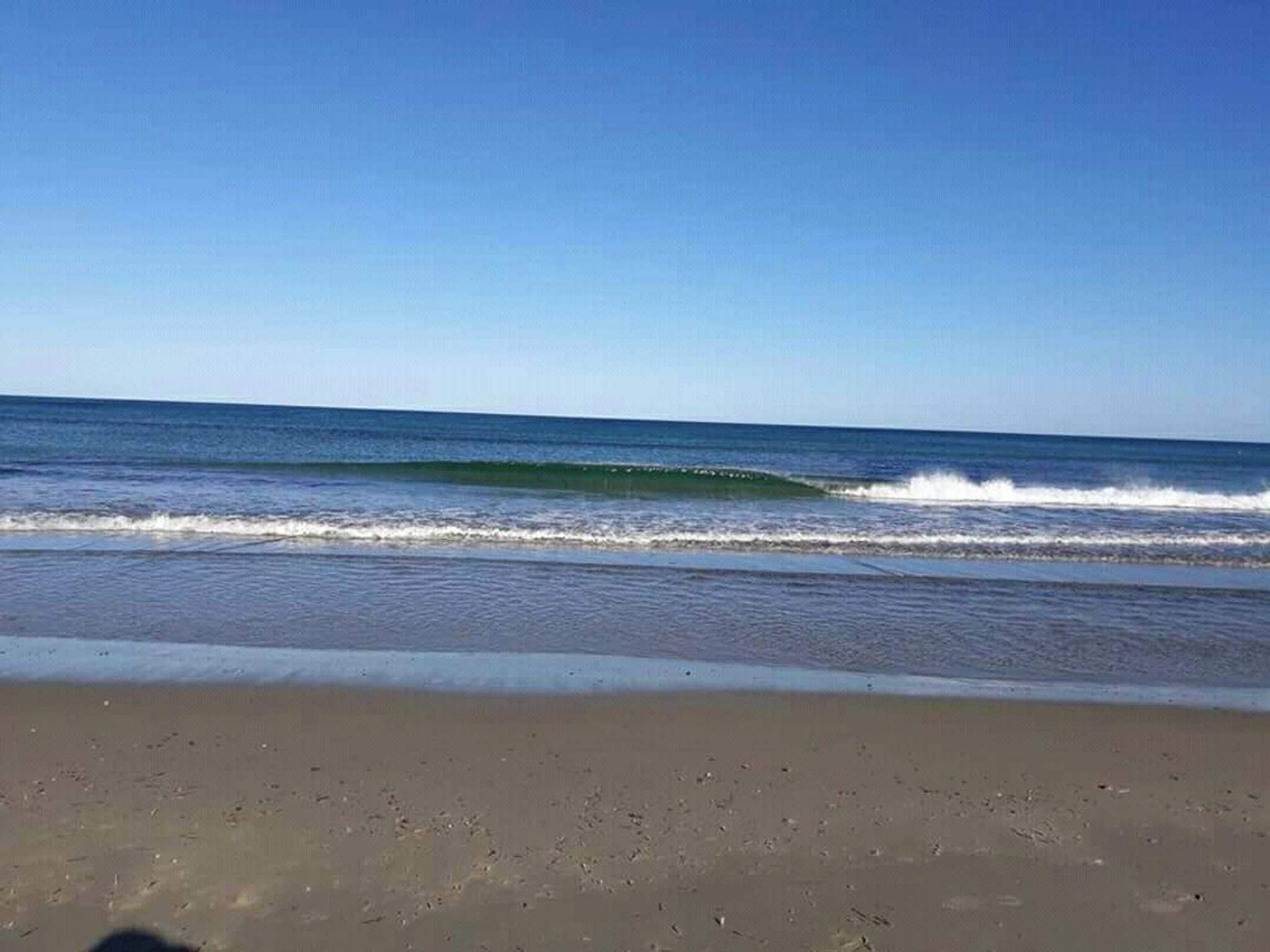A beach with waves and a clear sky.