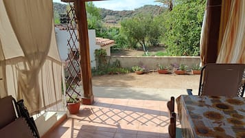 A patio with a view of a garden and hills.