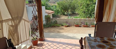 A patio with a view of a garden and hills.