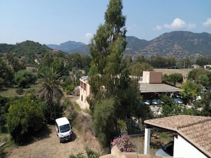 A rural landscape with a white van parked in a driveway, surrounded by trees and a building with a tiled roof. - Tertenia Ground Floor South 3 min Walk From the sea (Tertenia)