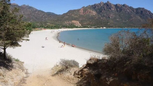 A beach with clear blue water, sandy shore, and mountains in the background. - Tertenia Ground Floor South 3 min Walk From the sea (Tertenia)