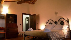 A bedroom with a bed, wooden dresser, and a door leading to another room. - Biofarm Podere Ficareto (Sovicille)