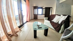 A living room with a glass coffee table, a sofa with cushions, and a view of the outdoors through large windows. - Sunny Cozy Home AMAZING SEA VIEW (Archanes-Asterousia)