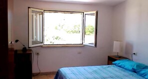 A bedroom with a bed, a desk, a chair, a lamp, and a window with an open shutter. - Always on Foot 3 min to the Beach Center With Double Terrace (Tertenia)