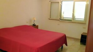 A room with a bed, a nightstand, a lamp, and a window. - Always on Foot 3 min to the Beach Center With Double Terrace (Tertenia)