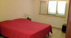 A room with a bed, a nightstand, a lamp, and a window. - Always on Foot 3 min to the Beach Center With Double Terrace (Tertenia)