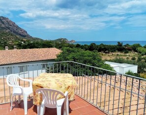 A balcony with a table and two chairs, overlooking a coastal landscape with a mountain and vegetation. - Always on Foot 3 min to the Beach Center With Double Terrace (Tertenia)