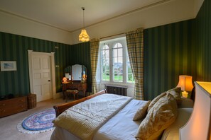 A bedroom with a bed, dresser, mirror, and window with curtains.
