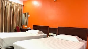 Hotellihuone, jossa on kaksi sänkyä, puinen pääty, työpöytä puhelimineen ja ikkuna, jossa on verhot.