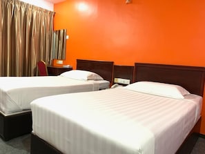 Une chambre d’hôtel avec deux lits, une tête de lit en bois, un bureau avec un téléphone et une fenêtre avec des rideaux.