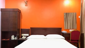 Hotellihuone, jossa on sänky, työpöytä, puhelin ja vaatekaappi.