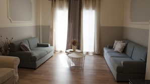 A living room with two sofas, a round coffee table, and an air conditioning unit.