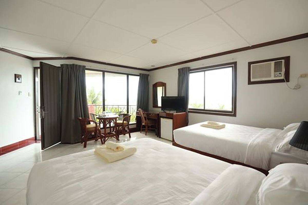 A hotel room with two beds, a desk, a chair, a TV, and a balcony.