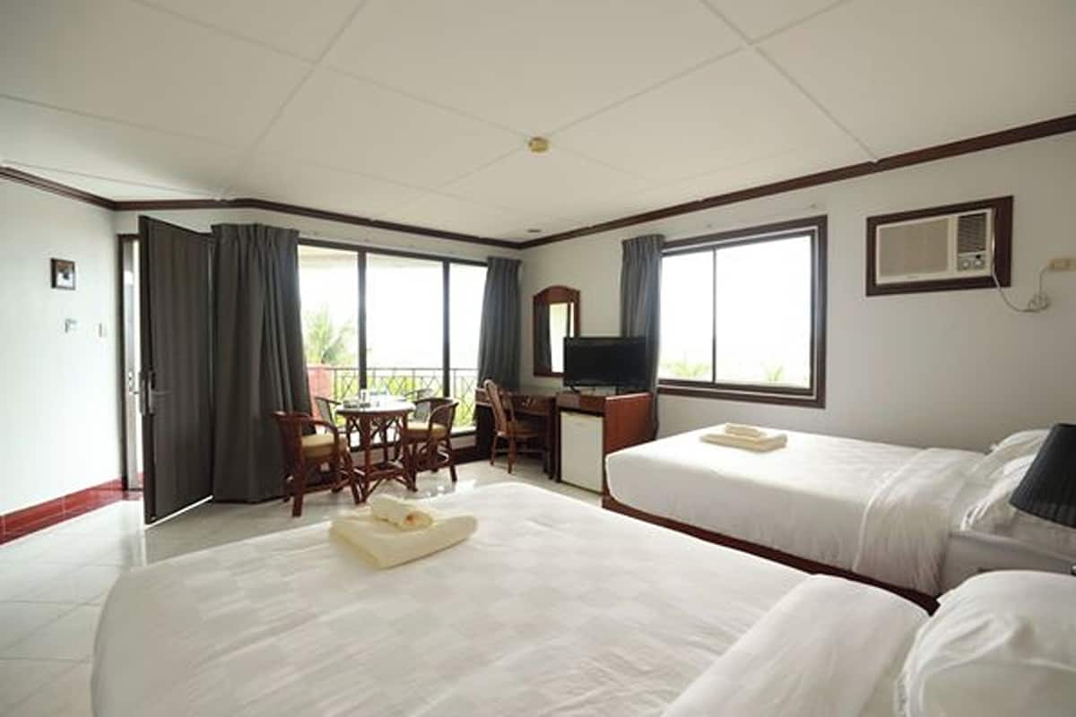 Habitación de hotel con dos camas, un escritorio, una silla, un televisor y un balcón.