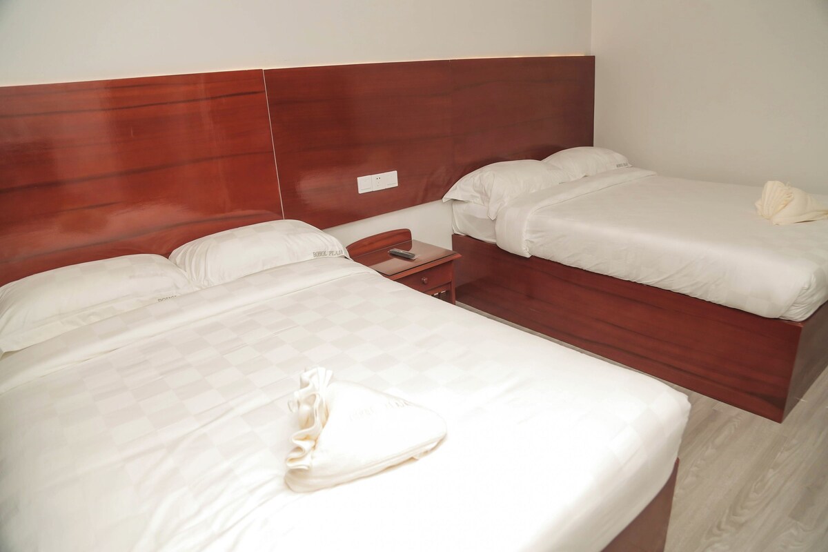 A hotel room with two beds, a wooden headboard, and a small bedside table.