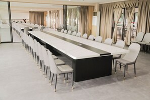 A conference room with a long table and chairs, large windows with curtains, and a modern design.