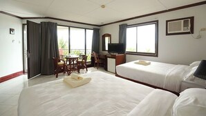 A hotel room with two beds, a desk, a chair, a TV, and a balcony. - Bohol Plaza Resort and Restaurant (Dauis)