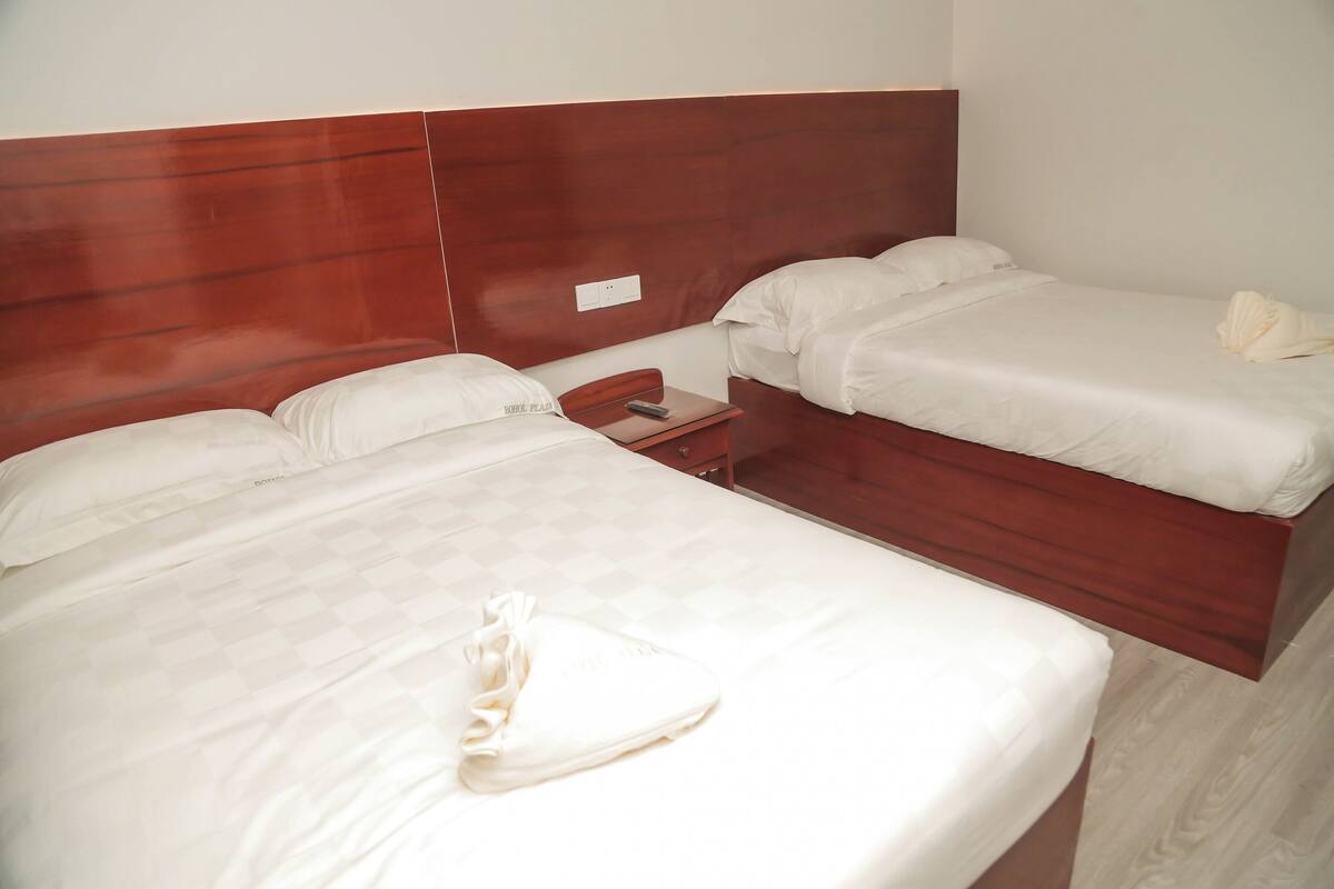 A hotel room with two beds, a wooden headboard, and a small bedside table.