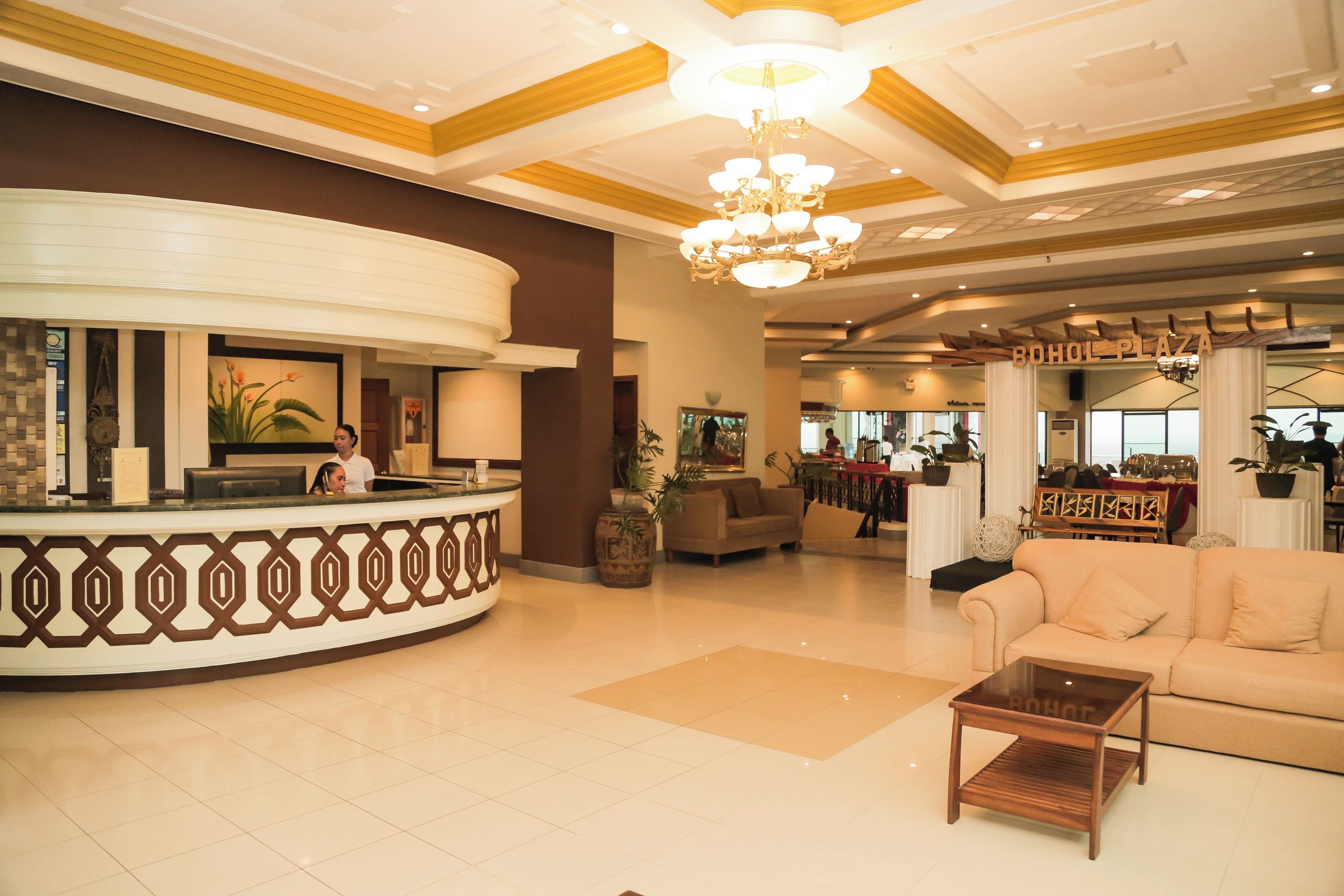 A lobby with a reception desk, a sofa, a coffee table, and a chandelier.