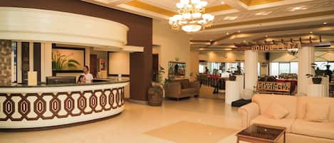 A lobby with a reception desk, a sofa, a coffee table, and a chandelier.