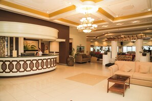 A lobby with a reception desk, a sofa, a coffee table, and a chandelier. - Bohol Plaza Resort and Restaurant (Dauis)