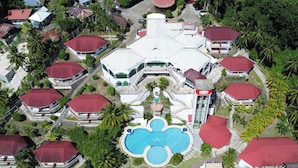 An aerial view of a resort with multiple buildings, a central swimming pool, and surrounding greenery. - Bohol Plaza Resort and Restaurant (Dauis)