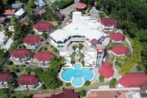 An aerial view of a resort with multiple buildings, a central swimming pool, and surrounding greenery. - Bohol Plaza Resort and Restaurant (Dauis)