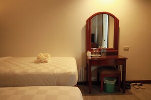 A hotel room with two beds, a wooden desk with a mirror, a trash bin, and a pair of slippers on the floor. - Bohol Plaza Resort and Restaurant (Dauis)
