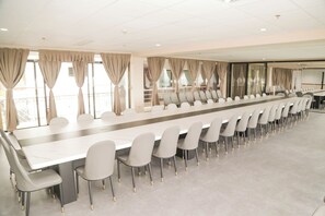 A conference room with a long table and chairs, large windows with curtains, and a balcony. - Bohol Plaza Resort and Restaurant (Dauis)